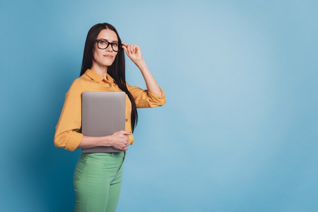 Молодой бизнес-леди с современным ноутбуком в строгой одежде на синем фоне