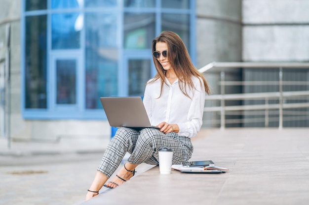 비즈니스 센터 근처 야외에서 노트북 작업을 하는 젊은 비즈니스 여성