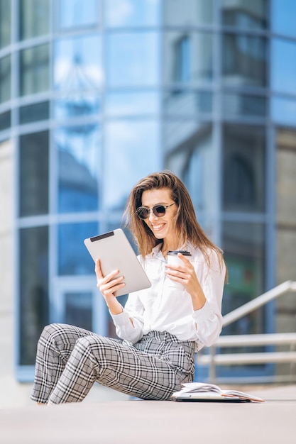 Giovane donna d'affari che lavora sul tablet all'aperto vicino al business center