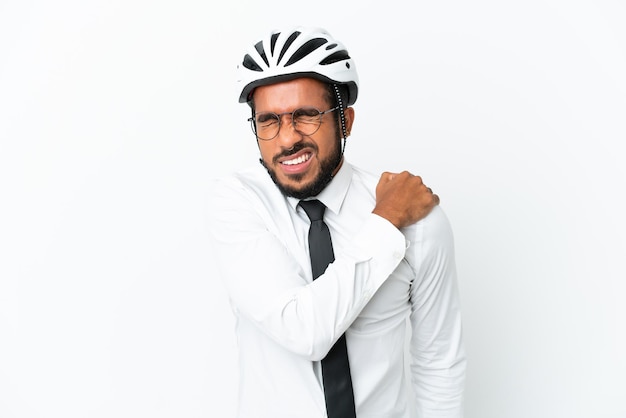 Young business latin man holding a bike helmet isolated on white background suffering from pain in shoulder for having made an effort