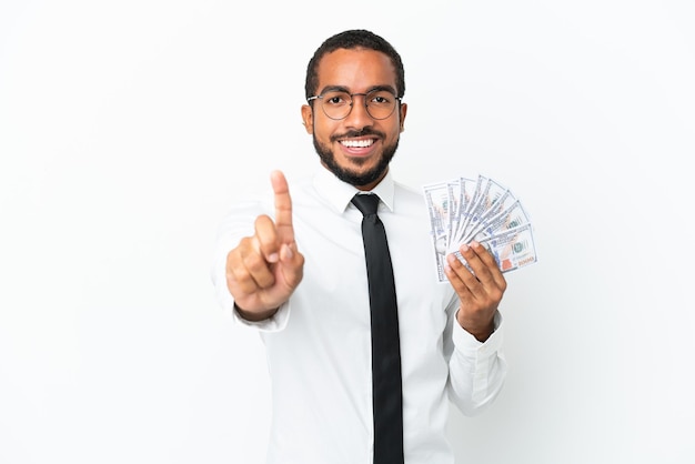 Young business latin man taking a lot of money isolated on white background showing and lifting a finger