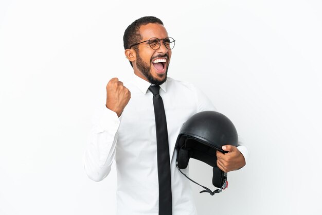 Young business latin man with a motorcycle helmet isolated on white background celebrating a victory