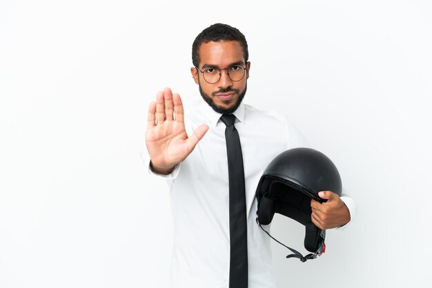 Young business latin man with a motorcycle helmet isolated on white background making stop gesture