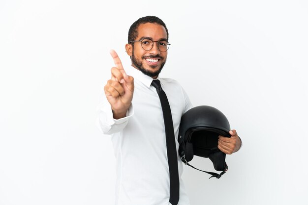 指を見せて持ち上げて白い背景で隔離のオートバイのヘルメットを持つ若いビジネスラテン男