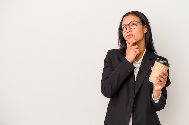 Young business latin woman holding a take away coffee isolated on white background  looking sideways with doubtful and skeptical expression.