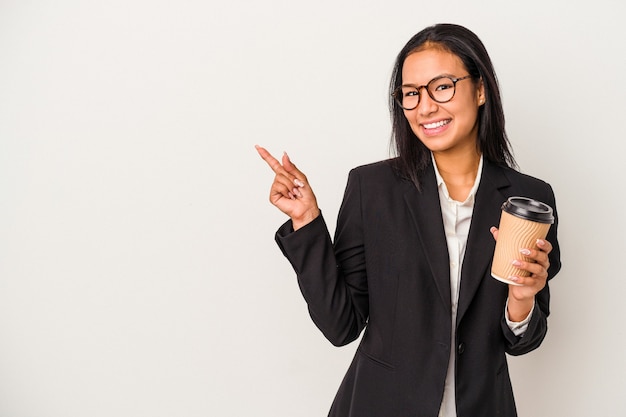 Young business latin woman holding a take away coffee isolated on white background  smiling and pointing aside, showing something at blank space.