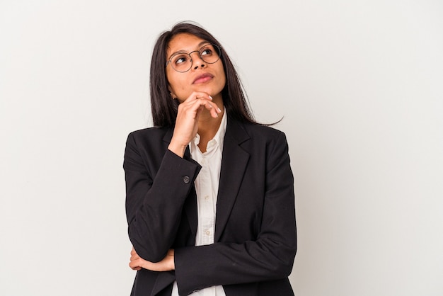 Young business latin woman isolated on white background looking sideways with doubtful and skeptical expression.