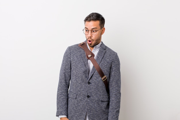 Young business man against a white wall being shocked because of something she has seen.