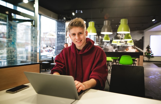 Young business man in casual clothes and sitting at a table in a fast food cafe