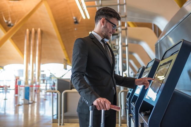 young business man doing self check in a machine at the airport 


