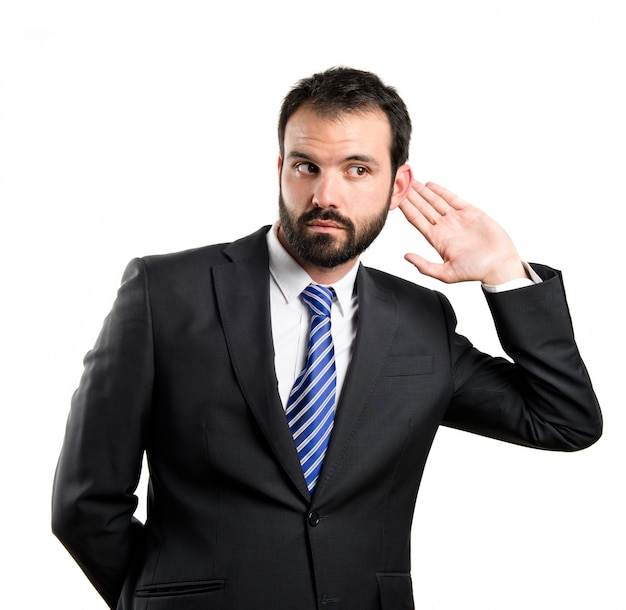 Young business man hearing something over white background 