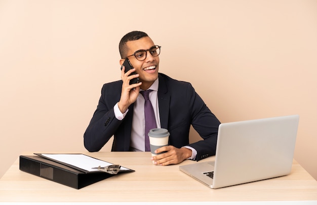 Young business man in his office with a laptop and other documents holding coffee to take away and a mobile