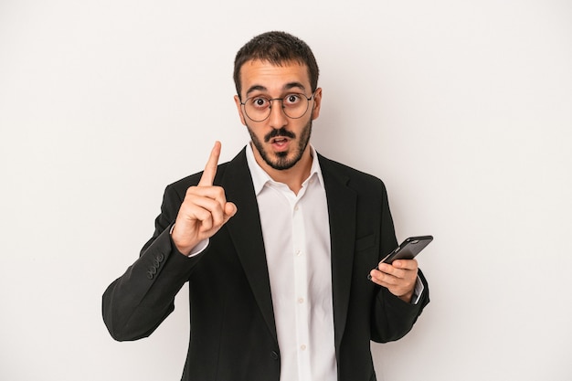 Young business man holding a mobile phone isolated on white background having an idea, inspiration concept.