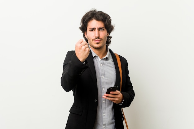 Young business man holding a phone showing fist with aggressive facial expression.