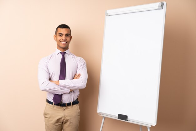 Young business man over isolated wall giving a presentation on white board and smiling