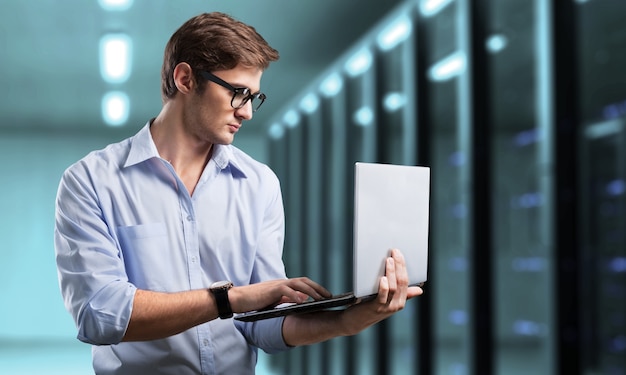 Young business man it engineer with aluminum laptop in server room