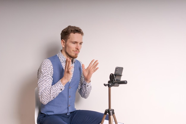 Young business man in shirt gesticulates while creating video in social