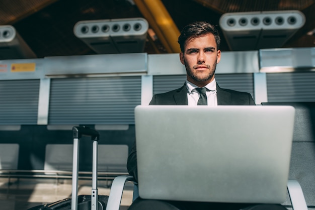 Young business man sitting on the computer with the suitcase at