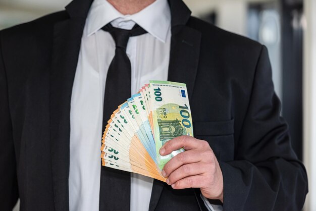 Photo young business man in a suit holding fan of euro banknotes business financial transaction