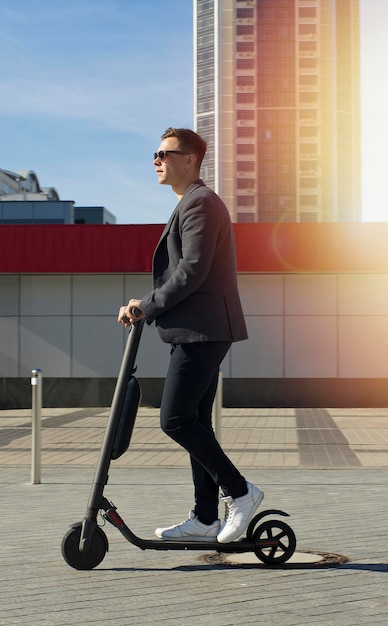 Young business man in a suit riding an electric scooter on a business meeting