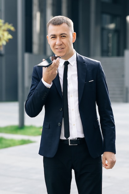 Young business man talking on phone near modern office building