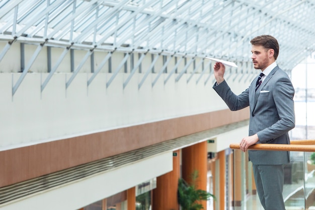 Young business man throwing a paper plane in office building