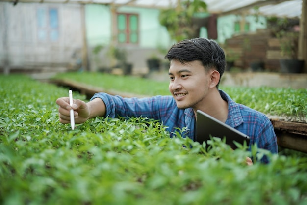 Giovane uomo d'affari che utilizza un tablet che controlla il concetto di foto di agricoltura digitale della fattoria