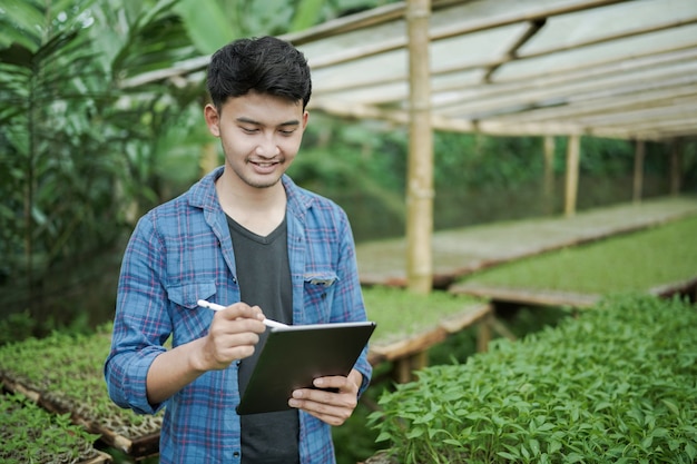 Giovane uomo d'affari che utilizza un tablet che controlla il concetto di foto di agricoltura digitale della fattoria