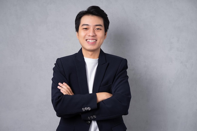 young business man wearing a suit posing on a grey background
