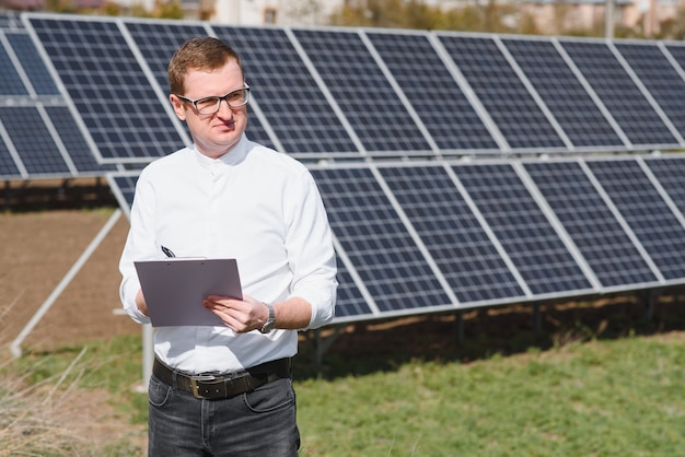 Young business man in a white shirt near the solar panels to power plants