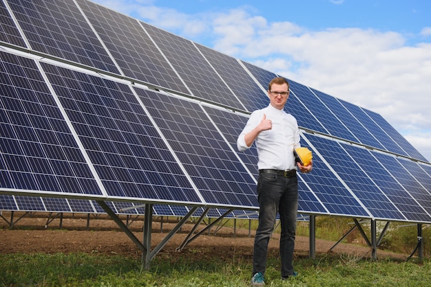 Young business man in a white shirt near the solar panels to power plants