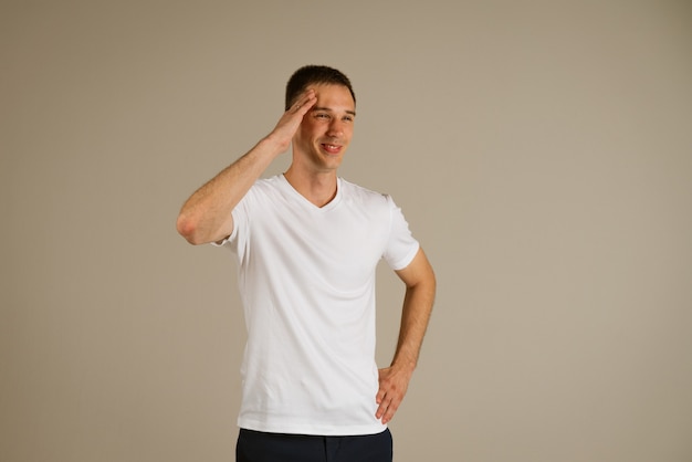 Young business man in a white tshirt gesturing with his hands on a light wall