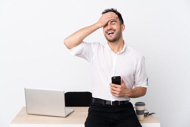 Young business man with a mobile phone in a workplace laughing