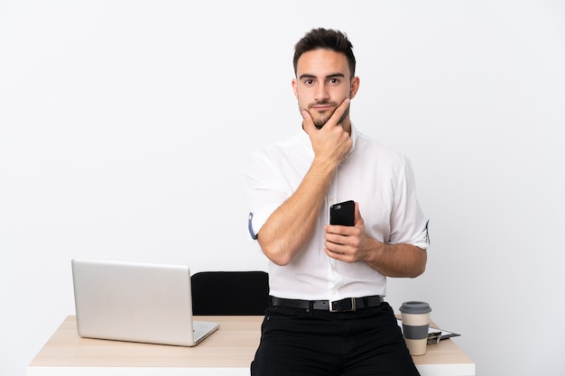 Young business man with a mobile phone in a workplace thinking an idea