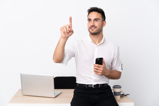 Uomo d'affari giovane con un telefono cellulare in un posto di lavoro toccando sullo schermo trasparente