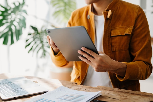 Young business man working at home office with laptop tablet and taking notes on the paper