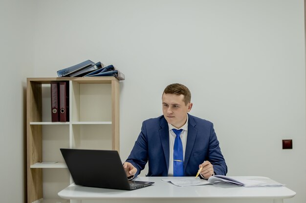 Young business man working at home with laptop and papers on desk
