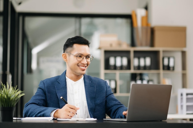 Young business man working at office with laptop tablet and taking notes on the paper in moderm office