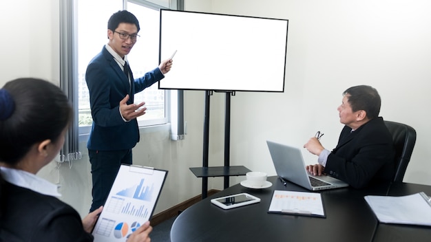 Presentazione di lavoro del giovane uomo di affari facendo uso del computer della televisione dello schermo in bianco