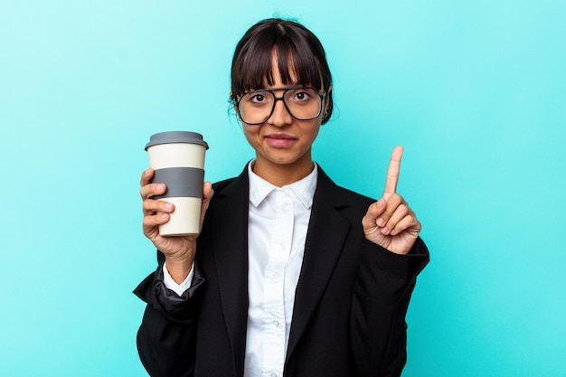 Молодой бизнес смешанной расы женщина, держащая кофе, изолированные на синем фоне, показывая номер один пальцем.
