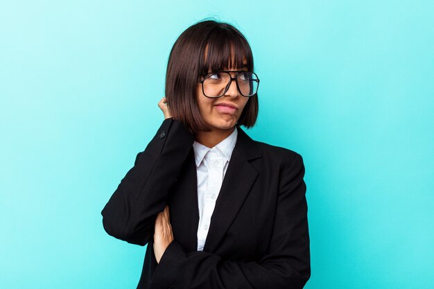 Young business mixed race woman isolated on blue background touching back of head, thinking and making a choice.