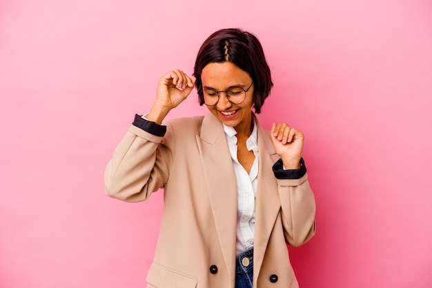 Young business mixed race woman isolated on pink background celebrating a special day, jumps and raise arms with energy.