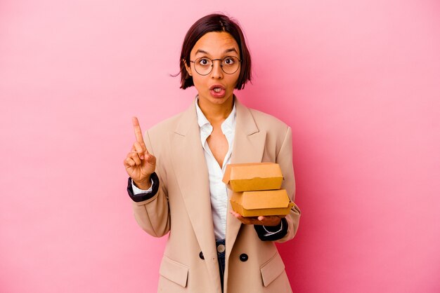 Young business mixed race woman isolated on pink wall having some great idea, concept of creativity.