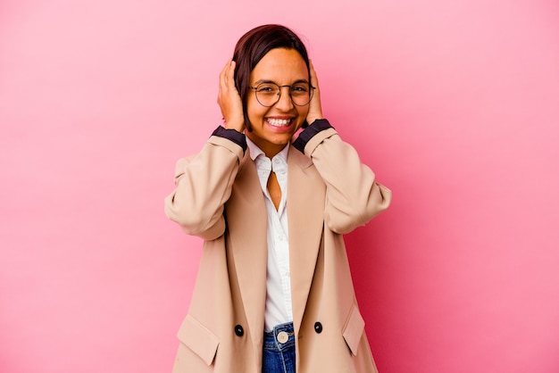 Young business mixed race woman isolated on pink wall laughs joyfully keeping hands on head