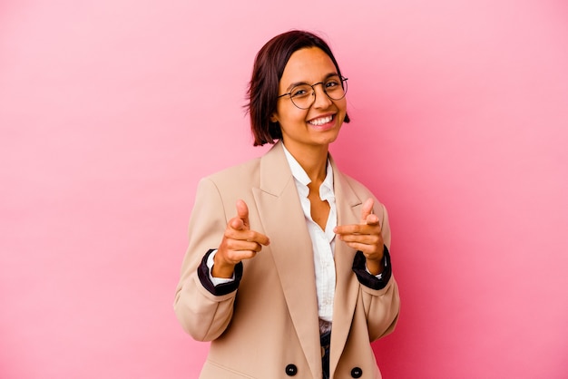 Young business mixed race woman isolated on pink wall pointing to front with fingers.