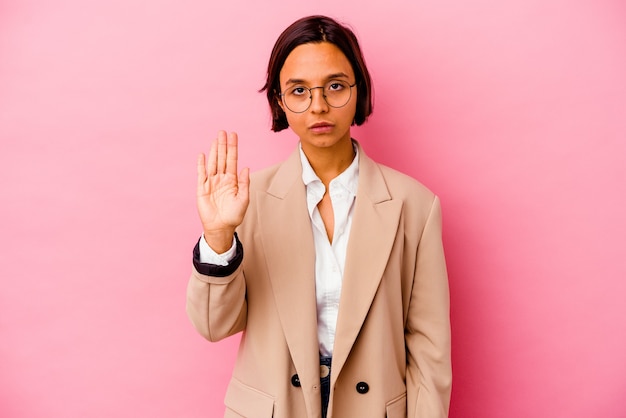 Молодая женщина смешанной расы бизнес, изолированные на розовой стене, стоя с протянутой рукой, показывая знак остановки, предотвращая вас.