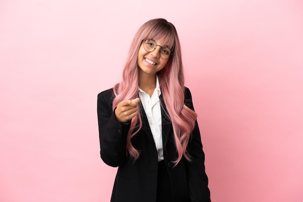 Young business mixed race woman with pink hair isolated on pink background points finger at you with a confident expression