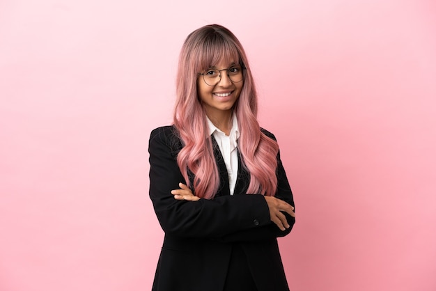 Young business mixed race woman with pink hair isolated on pink background with arms crossed and looking forward