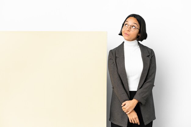 Young business mixed race woman with with a big banner isolated background and looking up