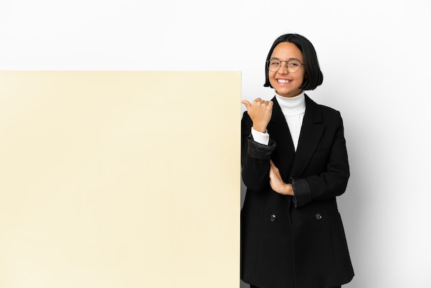 Young business mixed race woman with with a big banner over isolated background pointing to the side to present a product